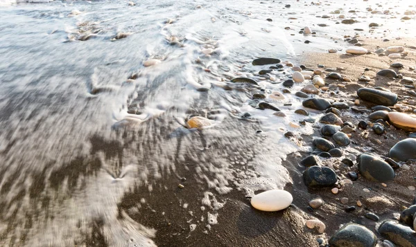 Guijarros ribereños en suave agua de mar lechosa —  Fotos de Stock