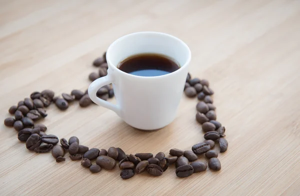 Grano de café y café negro dentro de un corazón — Foto de Stock