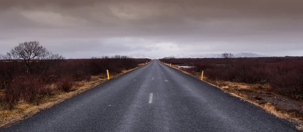 Carretera camino recto que conduce a las montañas nevadas —  Fotos de Stock