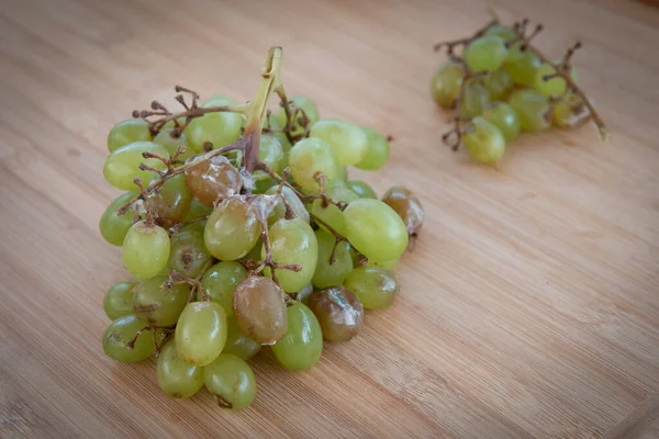 Frutas de uva murchas verdes insalubres em uma mesa. — Fotografia de Stock
