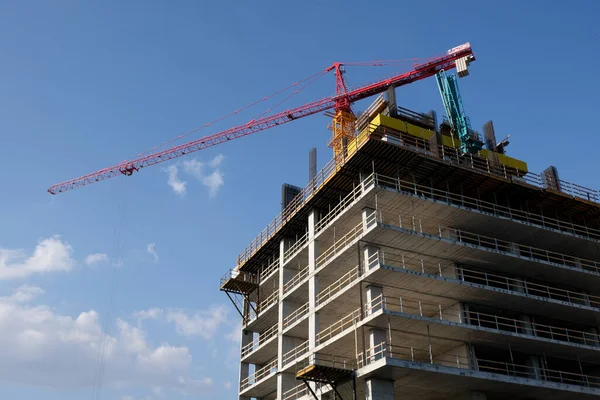 Mavi gökyüzünün ışıl ışıl olduğu bir günde modern İkamet Ofisi şantiyesi ve vinçler.