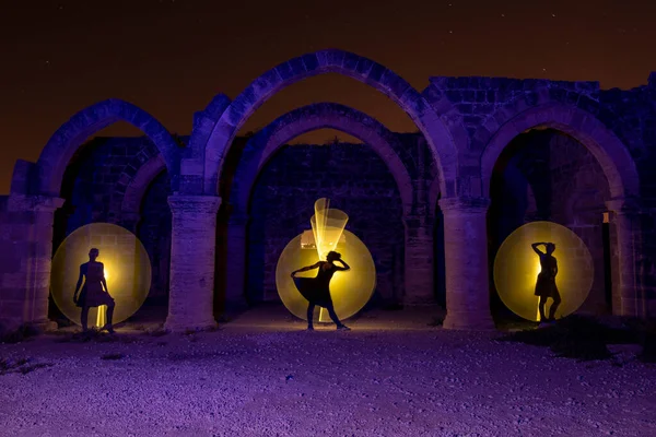 Young woman dancing below an old stoned column  with circle of painting light behind. Lightpainting photography