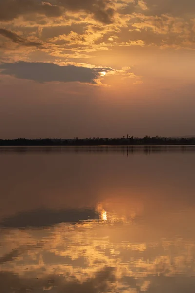 Sonnenuntergang mit Wolken am Himmel, die sich auf dem Wasser spiegeln — Stockfoto