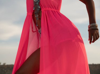 Kırmızı elbiseli Afrikalı model kadın modellik yapıyor ve poz veriyor.