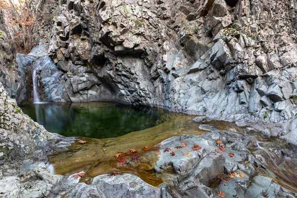 Cachoeira salpicando e fluindo através do rio com pedras no chão. — Fotografia de Stock
