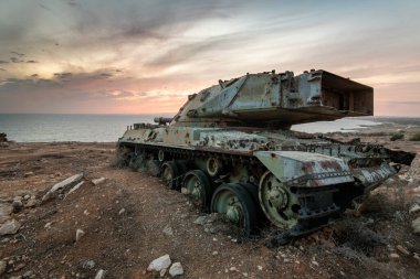 Gün batımında terk edilmiş askeri tank aracı. Hurda metal çevre kirliliği