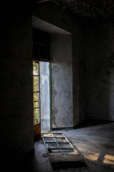 Abandoned room broken door and dramatic bright sunlight entering the place — Stock Photo, Image