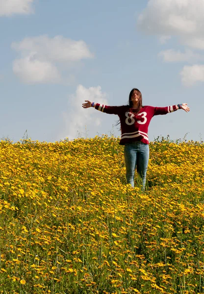 Menina feliz e um campo com flores amarelas na primavera — Fotografia de Stock