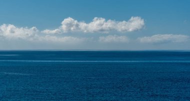 Turkuaz berrak mavi su ve beyaz bulutlu mavi gökyüzü.