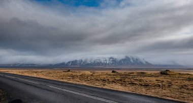 İzlanda 'nın baharında boş bir kırsal yol. Fırtınalı İzlanda manzarası