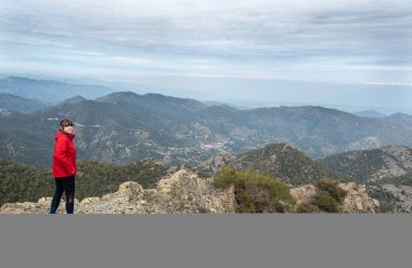 Kayalık tepede duran ve dağ manzarasının tadını çıkaran bir kadının arka görüntüsü. Gezinti ve tırmanış