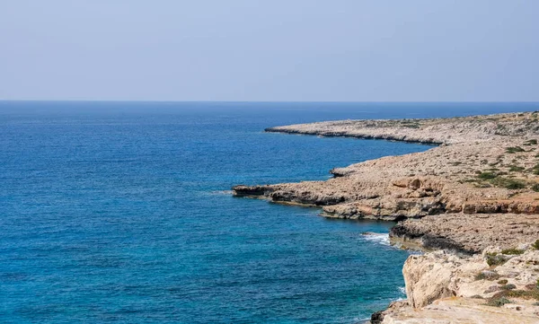 Costa rochosa com água azul e céu. — Fotografia de Stock