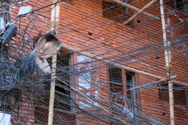 Dağınık elektrik ve elektrik kabloları bir binanın direklerine dolanmış. — Stok fotoğraf