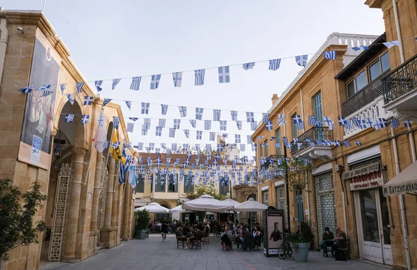 La gente se relaja en cafeterías y banderas griegas ondeando. Calle Leadra, Nicosia Chipre — Foto de Stock