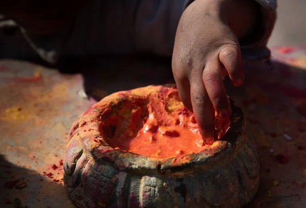 Çocuk eller konteynırdan turuncu renk seçiyor. Renk Festivali Nepal — Stok fotoğraf