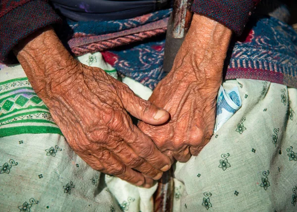 Nahaufnahme der gekreuzten faltigen Hände einer älteren nepalesischen Großmutter. — Stockfoto