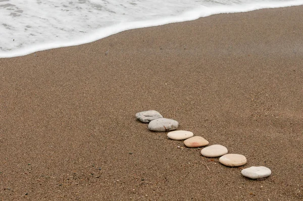 砂浜の海岸線と海の水の泡に生の滑らかなビーチ石. — ストック写真