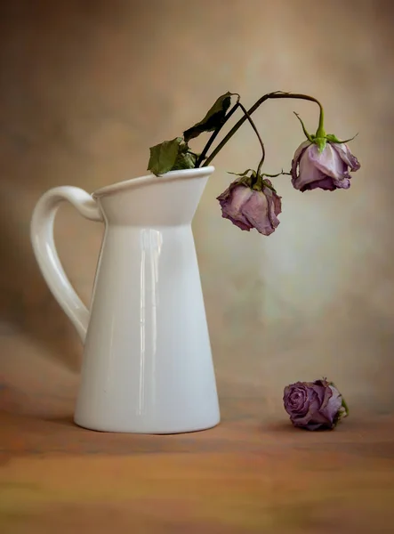 Trockene welke Rosenblüten auf einer weißen Vase und Vintage-Hintergrund — Stockfoto