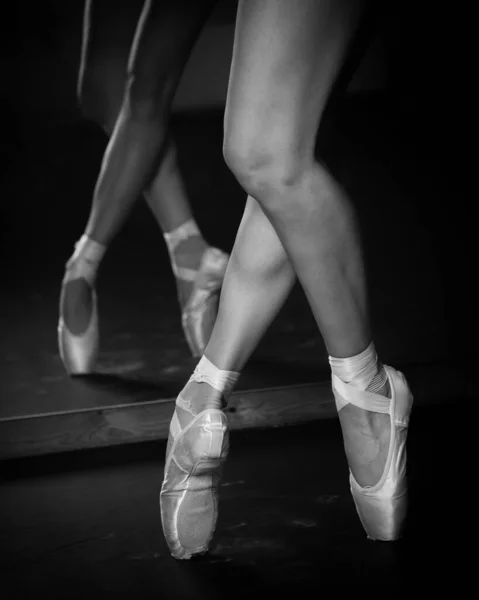 검은 바닥 배경에서 춤을 추고 있는 젊은 발레리나의 다리. 발레 연습. — 스톡 사진
