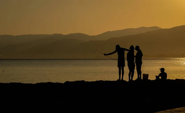 Vissers silhouet vissen in de kust bij zonnerijst. — Stockfoto