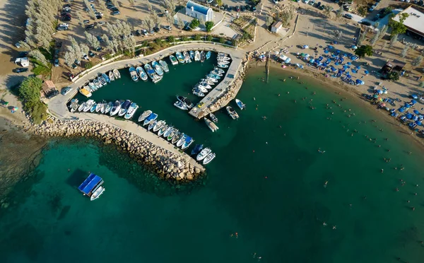 Flygdrönare utsikt över stranden med människor simning och fiskebåtar förtöjda vid hamnen. Protaras Paralimni Cypern — Stockfoto