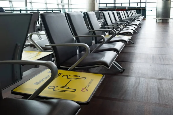 Amarelo sinal de distância social em cadeiras terminais no aeroporto. Medidas de segurança da pandemia de covid-19 — Fotografia de Stock