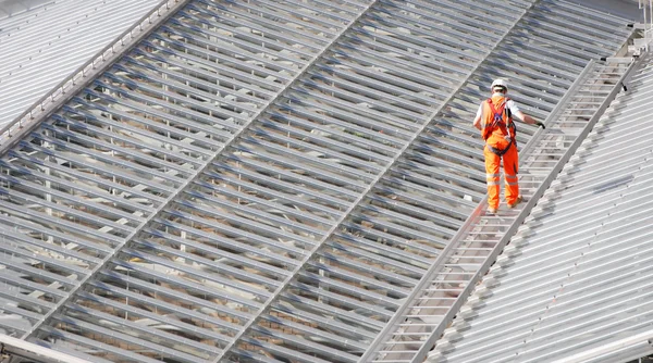 Trabalhador masculino andando em uma estrutura metálica do telhado — Fotografia de Stock