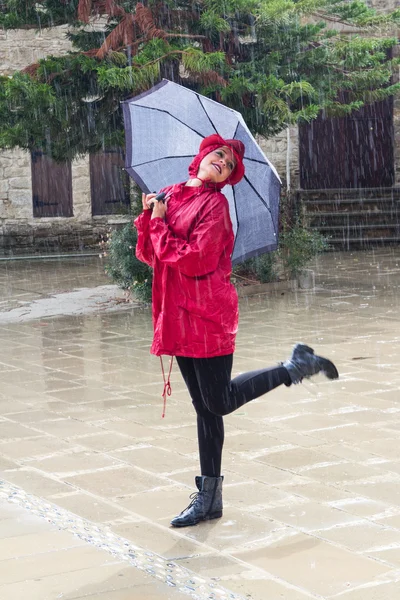 Yağmurda dans bir şemsiye olan mutlu kadın.
