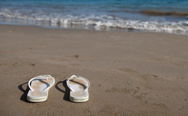 White sandals on a golden sandy beach 