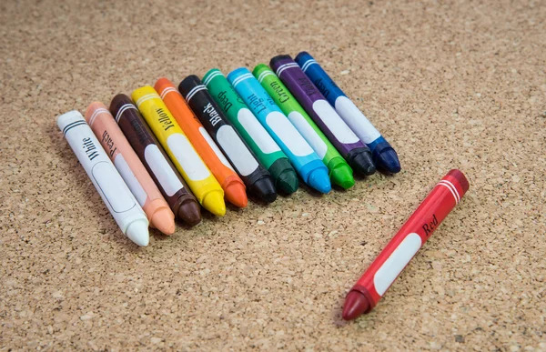 Colored drawing crayons on a cork board — Stock Photo, Image