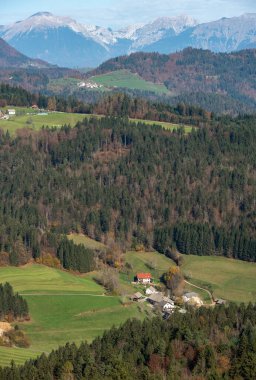 Sonbaharda vadide küçük bir köyle birlikte kayan tepeler, ormanlar ve dağ tepelerinin manzarası. Slovenya
