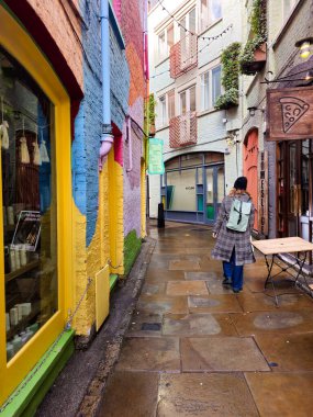 Londra, Birleşik Krallık, 23 Kasım 2025: Kadın, Neal 'ın bahçesinde renkli binalarla kaplı ıslak bir kaldırım taşı caddesi boyunca yürüyor. Londra Birleşik Krallık