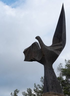 Lefkoşe, Kıbrıs, 17 Şubat 2024: Demir kartal heykeli bulutlu bir gökyüzüne karşı dimdik ayakta duruyor. Eserde yeşil ağaçlarla çevrili keskin açılar ve soyut şekiller yer alıyor. Kıbrıs Machairas Manastırı