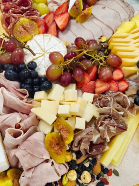 Şarküteri kurulu çeşitli peynirler sunar. Parti için hazırlanmış etler, fındıklar ve taze meyveler. Sağlıklı beslenme. Gıda başlatıcı