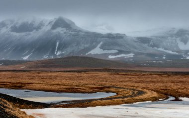 İzlanda dramatik manzarası, donmuş göl ve İzlanda 'da kar ve sisle kaplı dağlar.