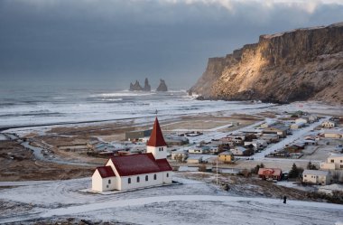 Icelandic village of Vik, Southeast Iceland with the VIk i Myrdal church at the top of the hill offering picturesque images of the community covered in Snow in Spring.