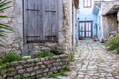 Geleneksel kaldırım taşı ara sokakları yıpranmış taş duvarlar ve binalar arasında dönüyor. Tarihi Lania Köyü mimarisi sergileniyor.