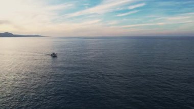 İHA 4k çözünürlüğündeki balıkçı teknesinin ufuk çizgisinde bir dağ silsilesiyle ya da günbatımında ya da gündoğumunda sakin bir okyanusta yelken açtığını gösteren görüntüler. Kıbrıs 'ta Akamas Paphos