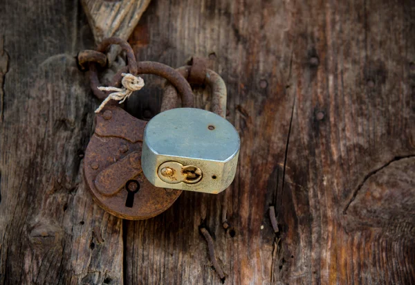 Metal rusty padlock on a closed old wooden door — Stock Photo, Image