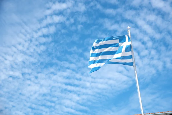 Yunan bayrağı mavi bir bulutlu gökyüzü karşı sallayarak — Stok fotoğraf