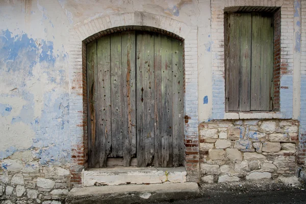 Ingang van een verlaten huis met groene deur en venster. — Stockfoto