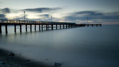 Dramatik bir bulutlu gün batımı sırasında iskele ile deniz manzarası 