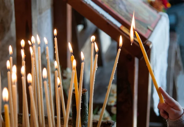 Velas da igreja com criança acendendo um para orar — Fotografia de Stock