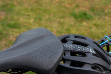 Bisikletin arka rafında duran siyah bir bisiklet kaskı..