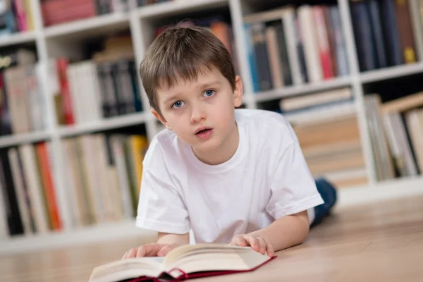 Kind liegt auf dem Bauch und liest ein Buch — Stockfoto