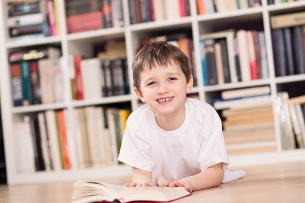 Усміхнена дитина читає книгу вдома . — стокове фото