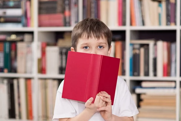 Criança esconde o rosto por trás do livro i — Fotografia de Stock