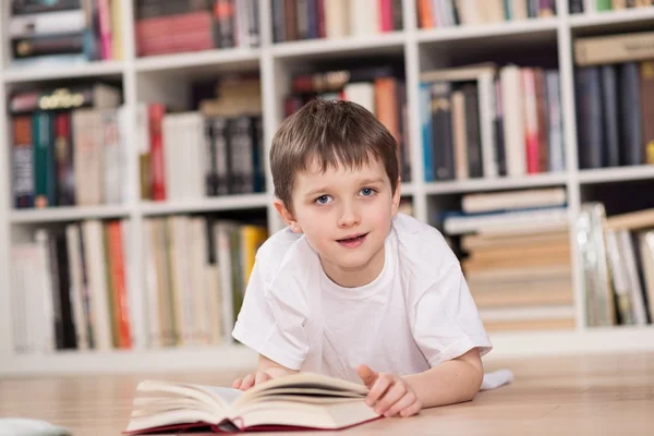 Gelukkig jongetje lezen van een boek thuis. — Stockfoto