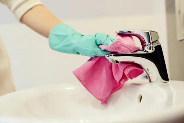 Mani femminili con guanti protettivi in gomma verde pulizia rubinetto — Foto Stock