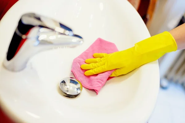 Frauenhände mit gelben Gummischutzhandschuhen reinigen Waschbecken — Stockfoto